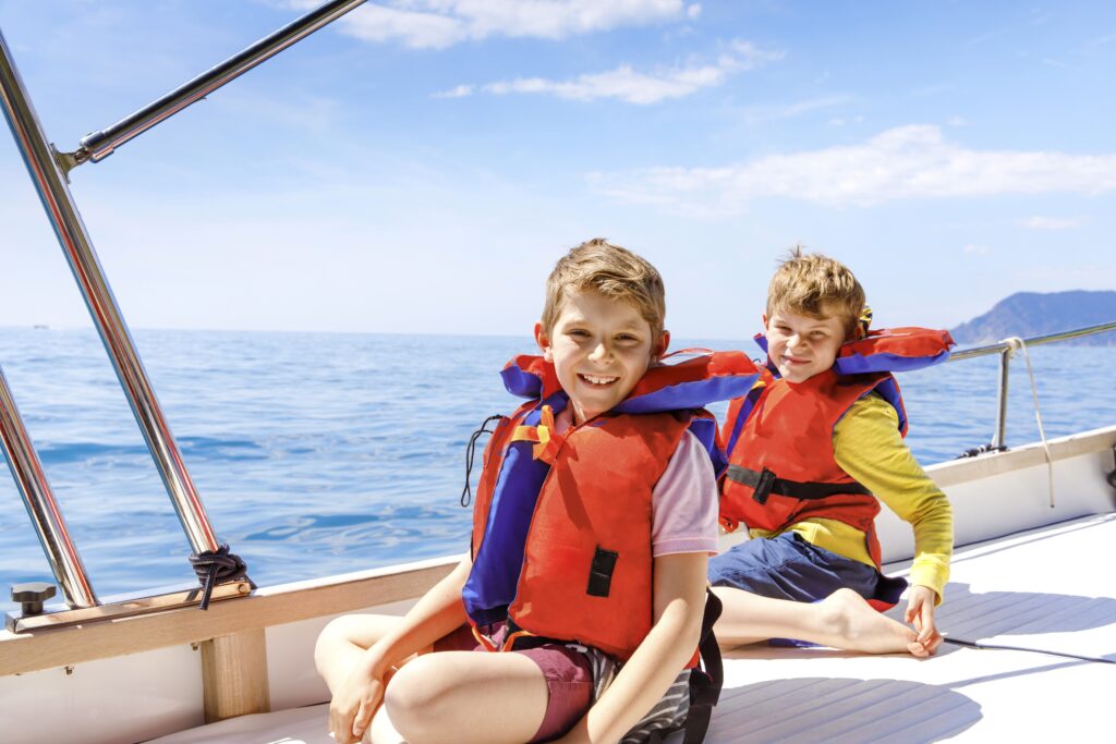 Two little kid boys, best friends enjoying sailing boat trip.