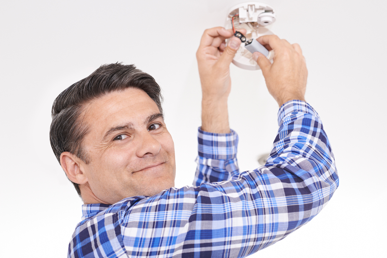 Man Replacing Battery In Home Smoke Alarm