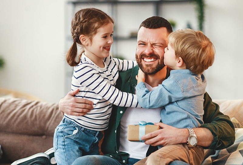 Father hugging two children all smiling and enjoying each other's company